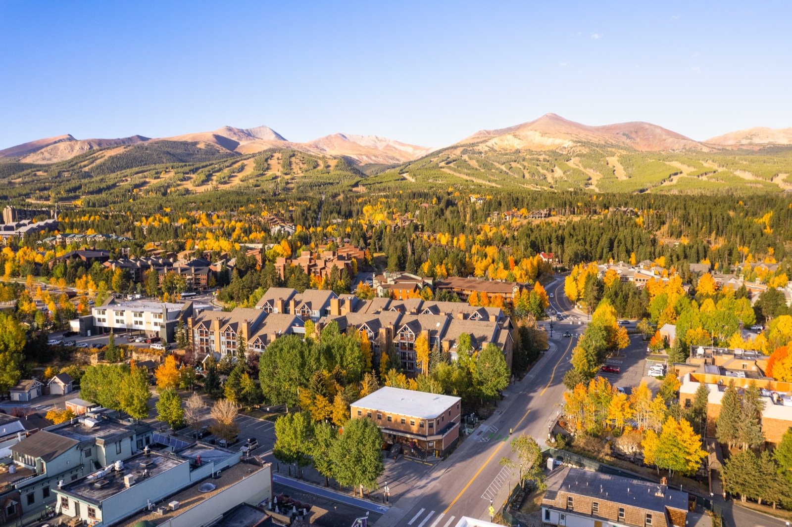 Aerial drone photo of Breckenridge, Colorado in fall with golden aspens and ski runs beyond