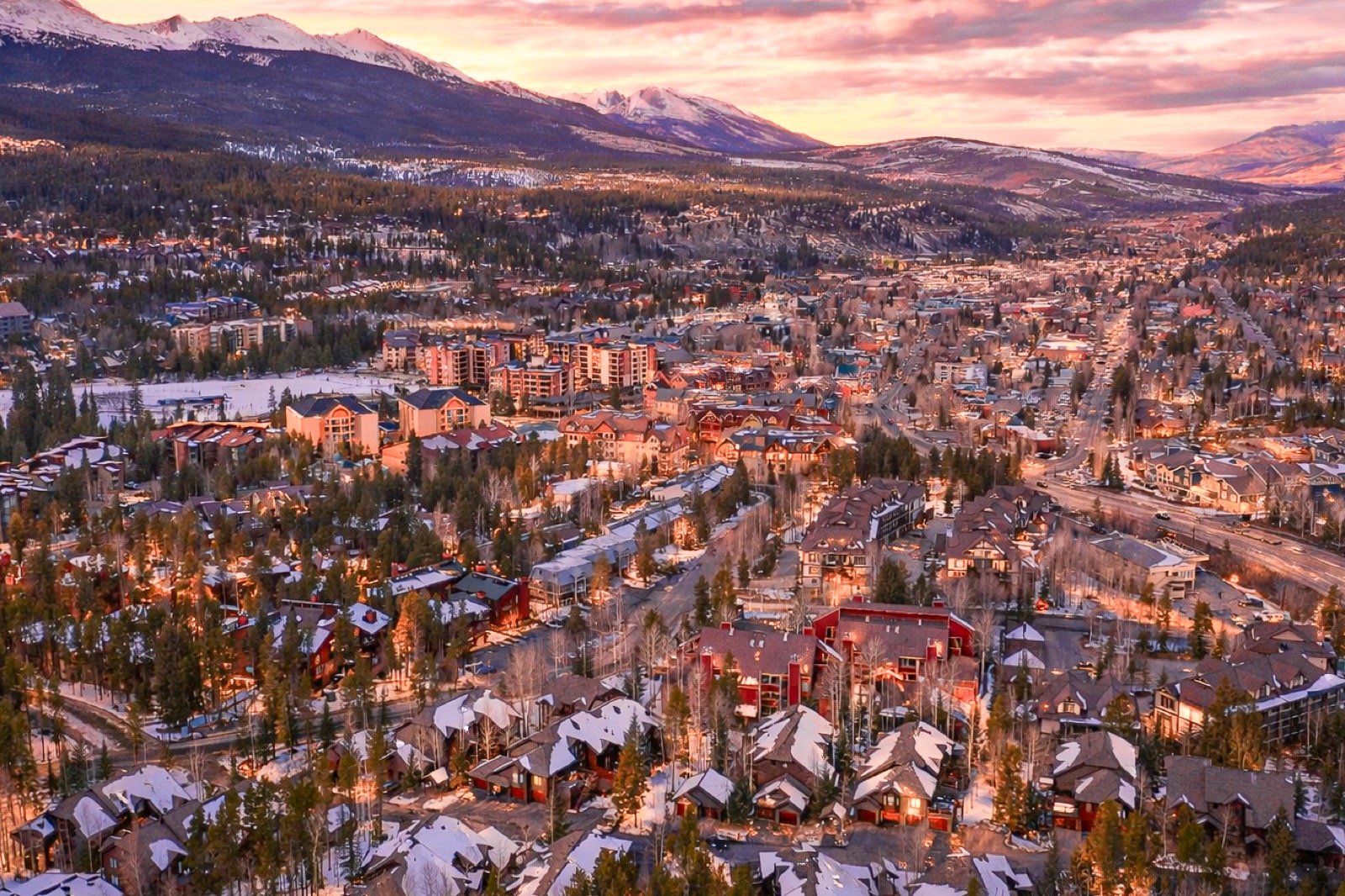 Aerial view of Breckenridge, Colorado at winter sunset — glowing town, snowy peaks, and alpenglow