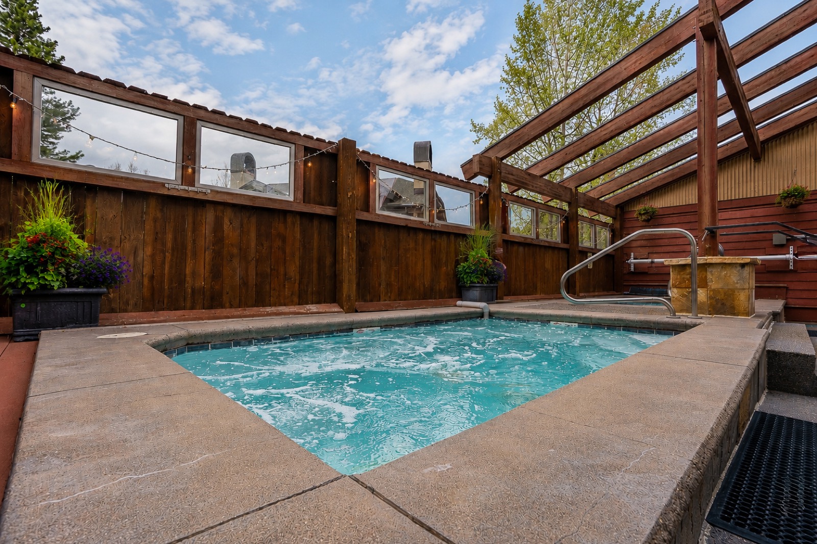 Outdoor community spa with wood pergola and privacy fence