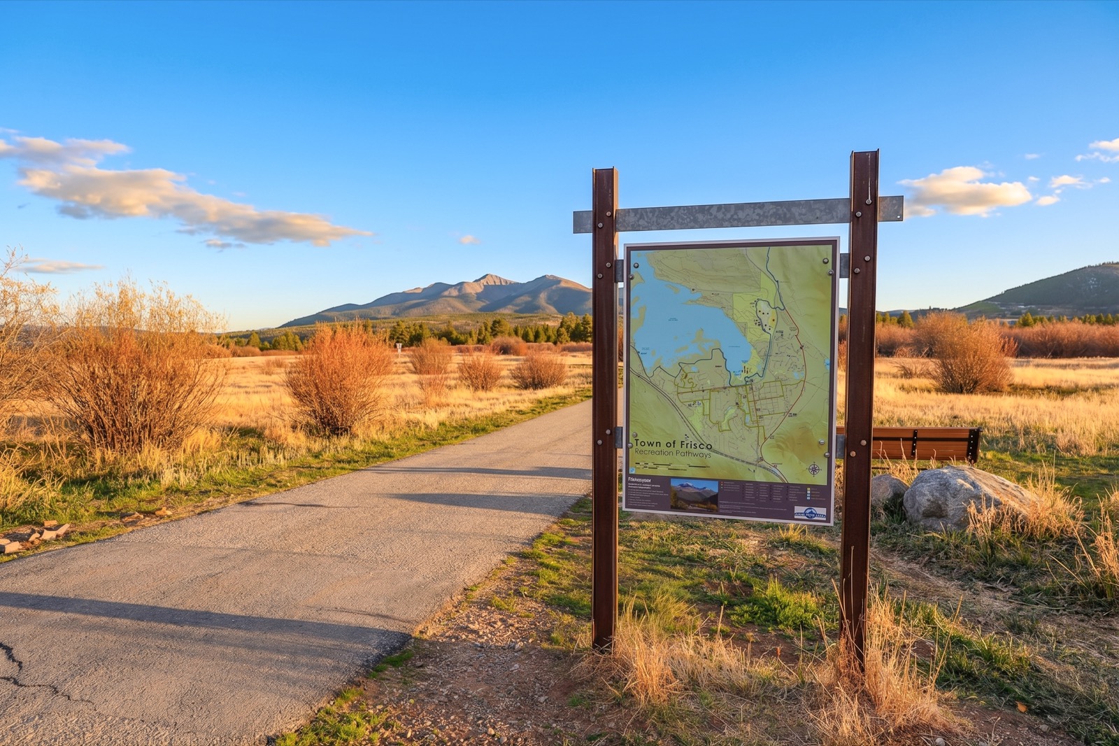 Recreation path and trail map sign with mountain backdrop at golden hour