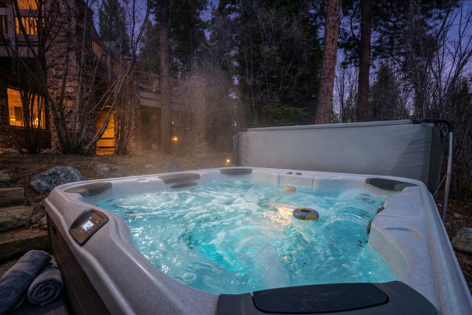 Steaming hot tub glowing at twilight beneath tall pines