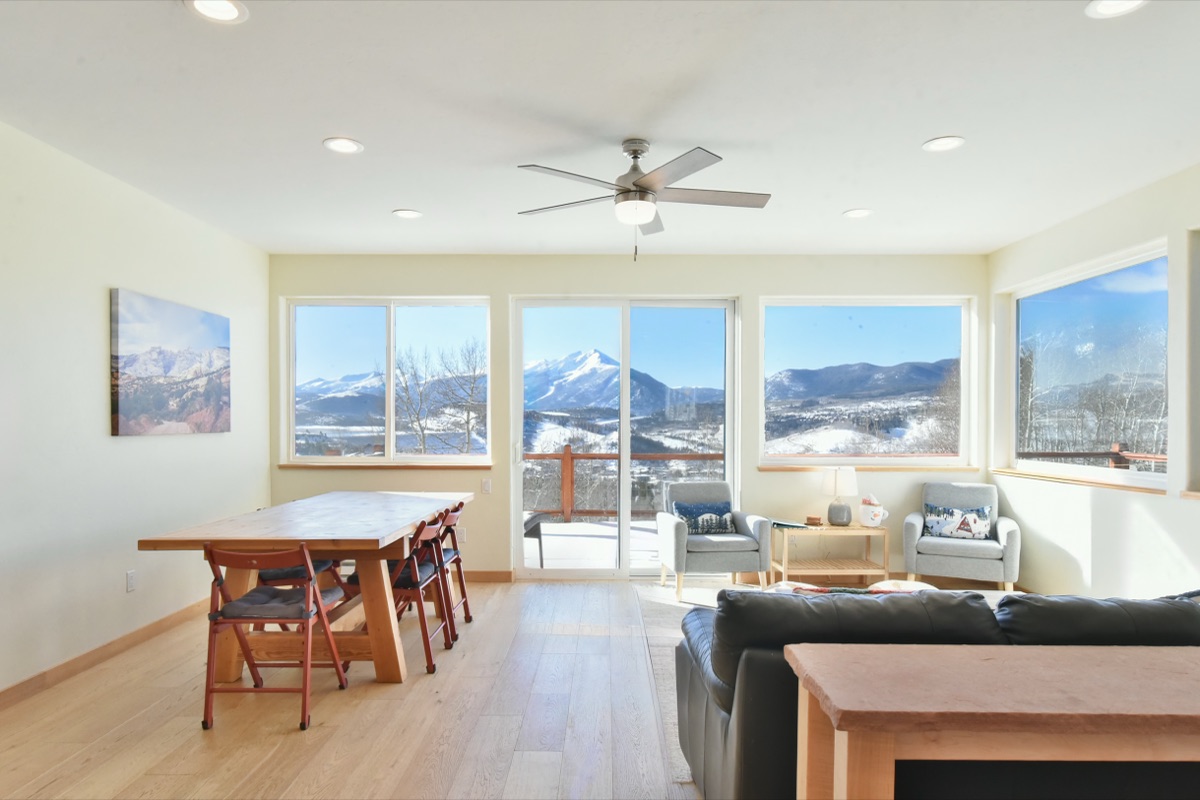 Open mountain-home living and dining room with a wall of windows framing the snow-capped Tenmile Range, Summit County Colorado